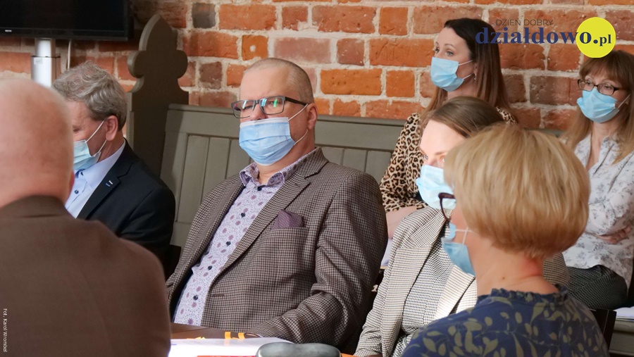 na pierwszym planie Adam Szczypiński radny miasta Działdowo, siedzi za stołem na sesji. obok niego siedzą pozostali uczennicy sesji